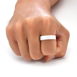 Close-up of a wide polished white ceramic ring shown on a hand in minimalist style