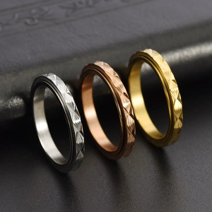 Dettaglio di tre anelli rotanti da 3mm in argento, oro e oro rosa con trama geometrica