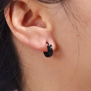 Close-up of black stainless steel Viking rune hoop earring worn on a male earlobe