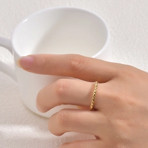 Detailed view of 18K gold-plated 2mm textured ring worn while holding a ceramic cup
