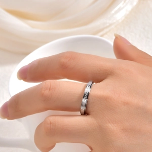 Gros plan d'une bague rotative en damier argenté portée au doigt au style minimaliste moderne