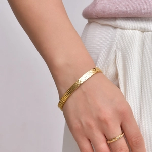 Detail of 18K gold plated cuff bracelet with vertical hammered texture on female wrist