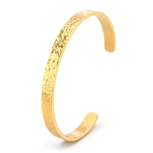 Detailed close-up of the hammered texture on a golden C-shaped stainless steel cuff bracelet