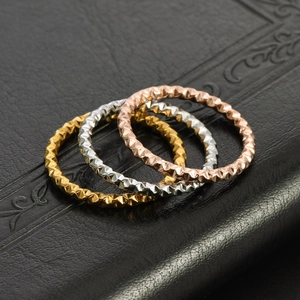 Detailed view of three 18K gold-plated rings with textured diamond-cut surface pattern
