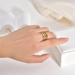Close-up of golden triple-layered stacked rings on index finger with elegant packaging