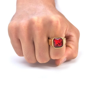 Macro detail of men's gold signet ring with a square step-cut red gemstone on a hand