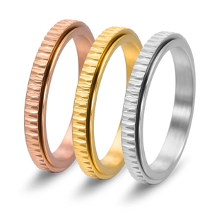 Detail of three spinner rings in gold, silver, and rose gold with diagonal textures