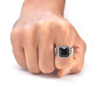 Close-up of a silver men's ring with a large square black gemstone and wide band