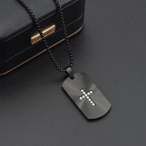 Detail eines schwarzen Dog-Tag-Anhängers mit Diamantkreuz und strahlenförmigen Linien