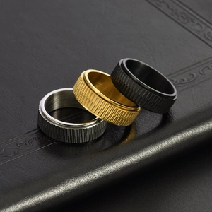 Close-up of spinning stainless steel rings in silver, gold, and black with gear textures