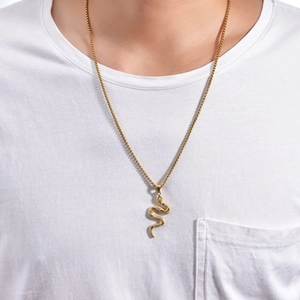 Dettaglio di un ciondolo cobra dorato con scaglie definite su una catena a maglia quadrata
