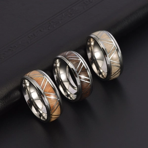 Titanium steel ring with wood inlay showing triangular geometric cut on dark background