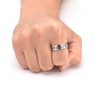 Macro shot of silver Viking rune cut-out stainless steel ring worn on a person's finger