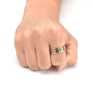 Detail of men's gold stainless steel ring with black and gold checkerboard pattern