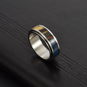 Macro view of men's stainless steel ring with rainbow wood grain inlay on black leather