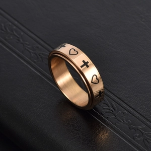 Detail of rose gold spinner ring with engraved black heart and cross symbols