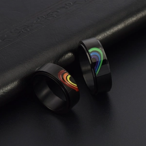 Macro shot of black spinner rings forming a rainbow heart on dark leather background