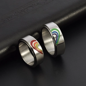 Close-up of matching stainless steel couple rings with rainbow enamel heart design