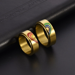 Close-up of golden stainless steel couples rings with rainbow enamel heart design