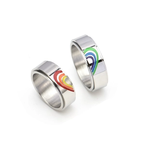 Close-up of interlocking heart-shaped rainbow enamel pattern on stainless steel spinner rings