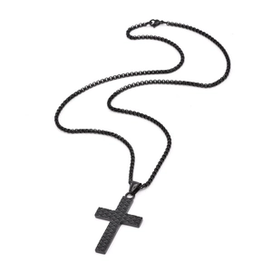 Detailed view of matte black steel cross pendant with textured eye pattern and ball chain