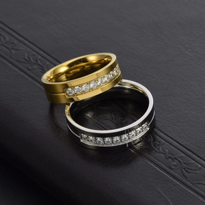 Partnerringe aus Titanstahl in Gold und Silber mit Kristallen auf schwarzem Lederhintergrund