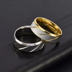 Macro shot of 8mm brushed steel rings with diagonal grooved finish and gold accents