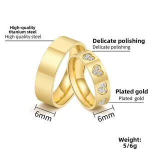 Detail of 6mm titanium steel couple rings with heart shape zircon inlay in gold finish