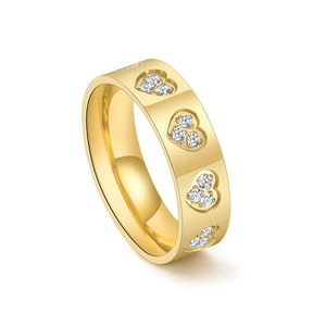 Detailed view of golden wide ring featuring engraved heart shapes set with clear diamonds