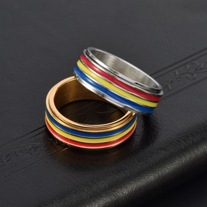 Detail of spinning stainless steel rings with colorful enamel stripes on black leather