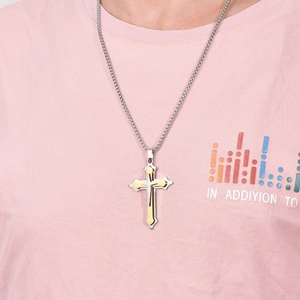 Close-up of double-layered cross pendant in gold and silver finish on a round neck tee