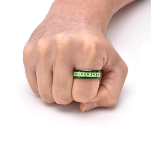 Macro detail of black stainless steel ring featuring glowing green moon and star patterns