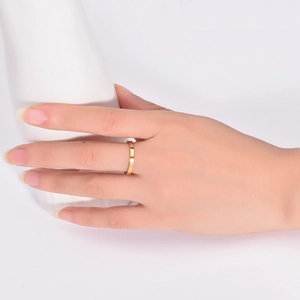 Close-up of minimalist 2mm gold titanium steel ring worn on finger with smooth finish