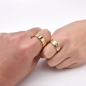 Macro detail of gold-plated couple rings featuring a smooth band and heart-shaped diamond setting