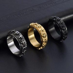 Macro detail of gothic skull and cross spinner rings in silver, gold and black finish