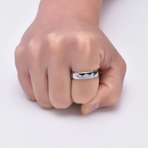 Vue macro d'une bague large argentée avec facettes géométriques sur une main d'homme