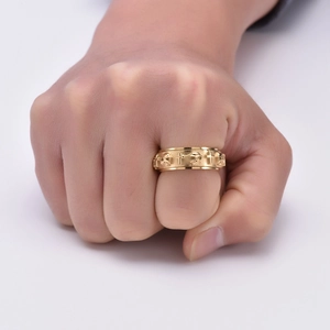 Detailed close-up of gold skull and cross spinner ring on finger showing gothic relief