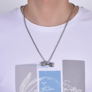 Gros plan d'un collier pendentif haltère en argent sur un mannequin avec chaîne à billes