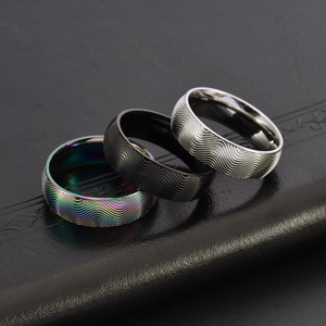 Gros plan de bagues en acier avec texture ondulée en finitions irisées, noires et argent