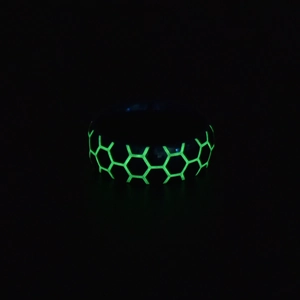 Close-up of men's luminous football ring with green glowing honeycomb pattern in dark