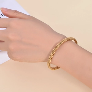 Detailed view of golden braided C-shaped cuff bracelet showing intricate woven metal texture
