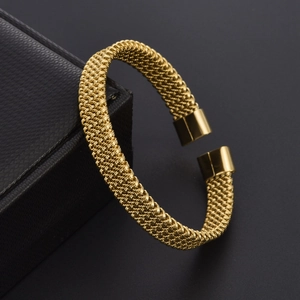 Detailed macro view of woven texture and polished ends on a golden C-shaped cuff bracelet