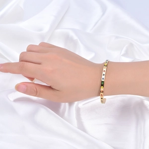 Détail d'un bracelet jonc doré en C avec empreintes de pattes arc-en-ciel sur fond de soie