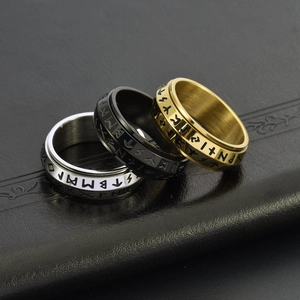Close-up of three rotating Viking rune rings in silver, black and gold steel