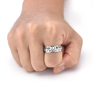 Close-up of vintage Viking runes on a silver spinning ring worn on a man's finger
