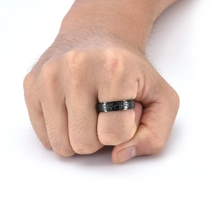 Dettaglio dell'anello rotante nero con trama in pietra su un dito maschile, titanio