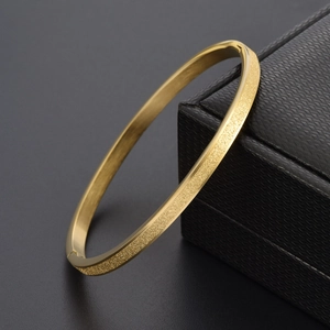 Détail d'un bracelet doré 18K avec finition givrée sablée et bords intérieurs polis miroirs
