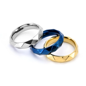 Macro view of geometric faceted rings in silver, blue, and gold with polished finish