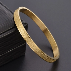 Détail du bracelet doré mat givré avec fermoir sécurisé posé sur un écrin noir