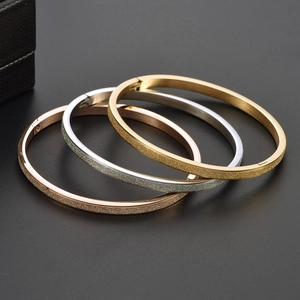 Gros plan de trois bracelets mats en or, argent et or rose avec fermoir à charnière poli